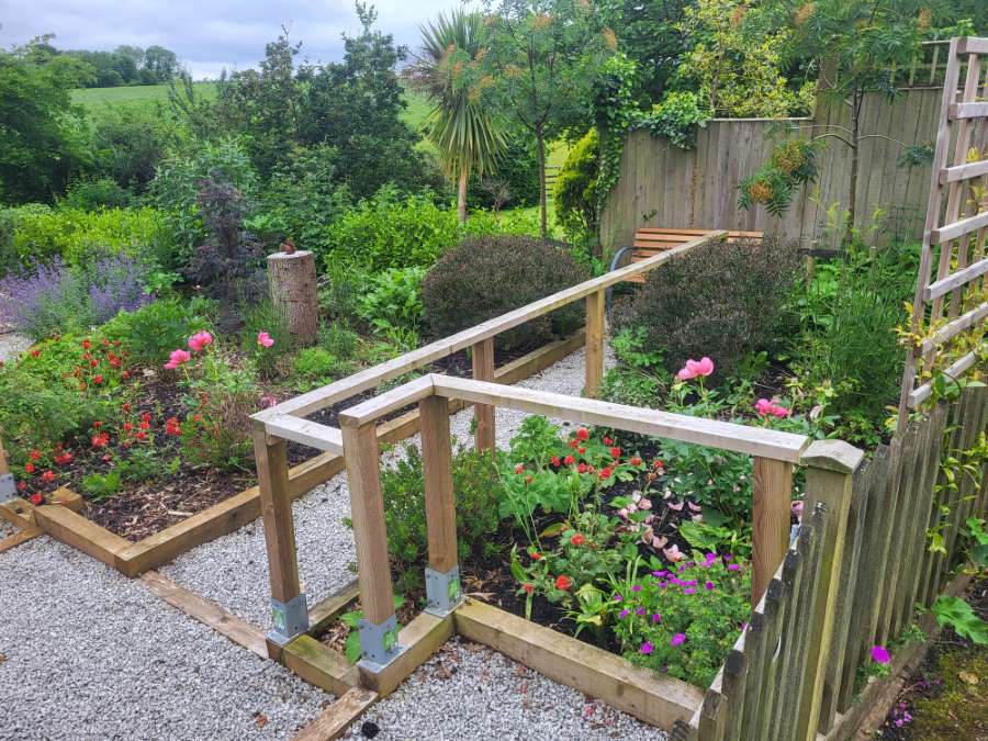 Beautiful country garden with path and wooden rails.