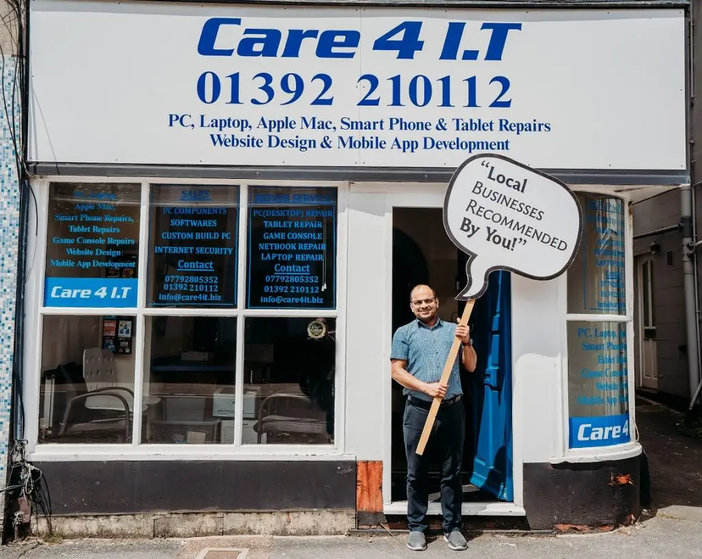 Man standing outside Computer Repair Shop holding sign 'local businesses recommended by you'