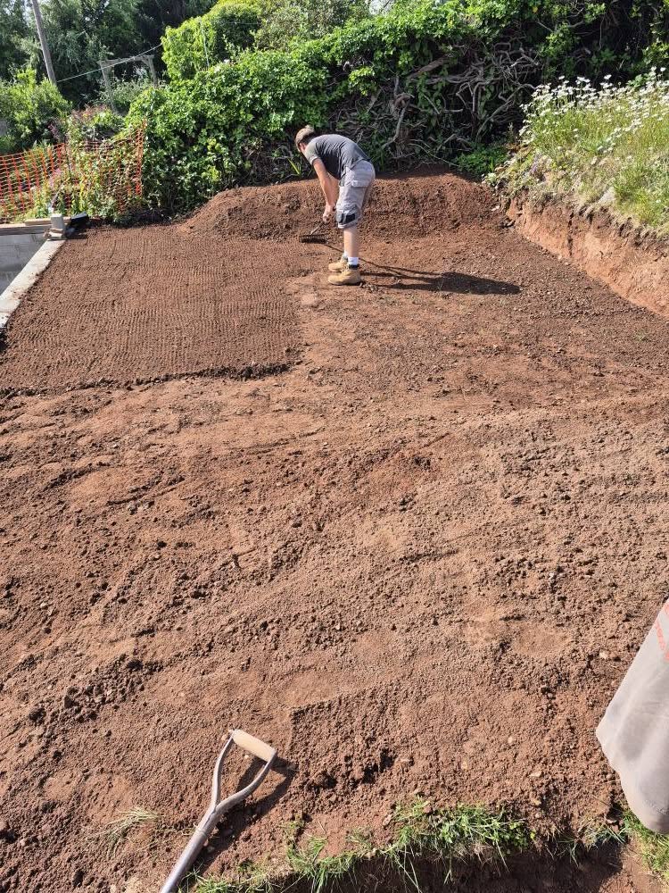 Preparing base for patio - man raking soil flat.