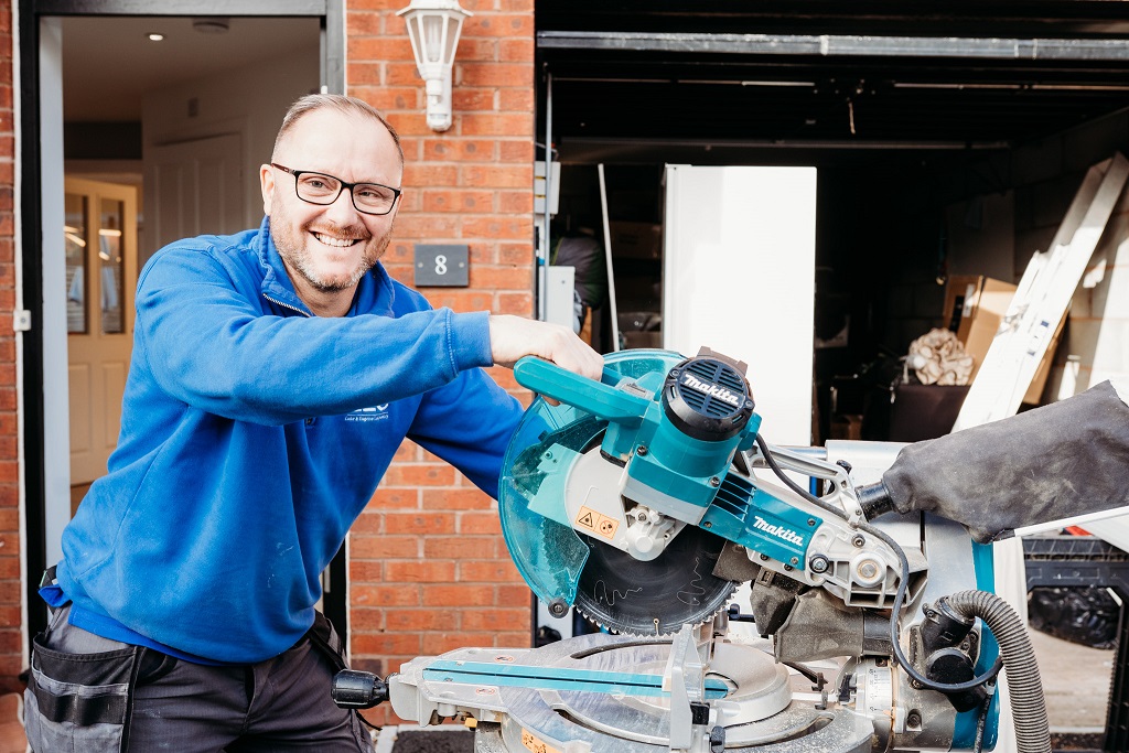Smiling carpenter holding circular saw