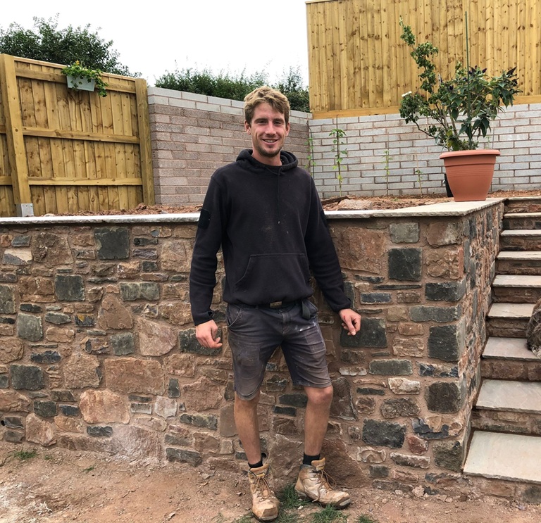Proud Honiton builder in front of stone wall