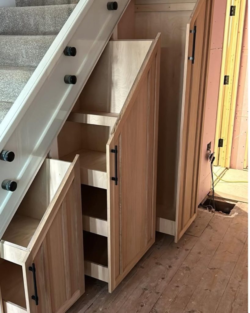 Clever understairs pull-out storage solution made by carpenter out of wood.