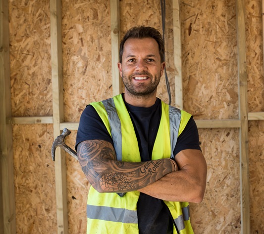 Smiling builder holding hammer facing camera