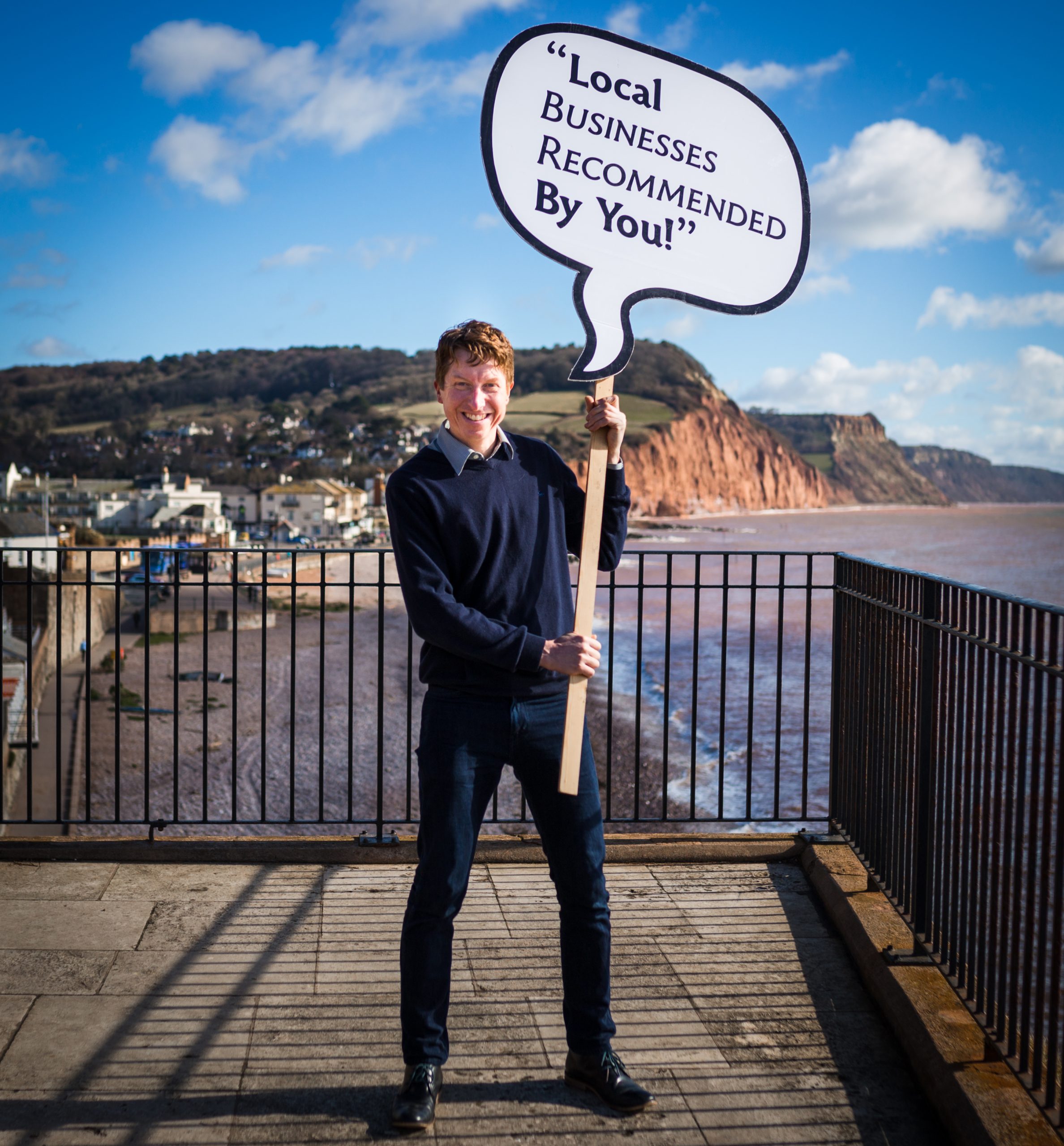 Nick Local Expert with Sidmouth behind him - holding sign 'local businesses recommended by you'